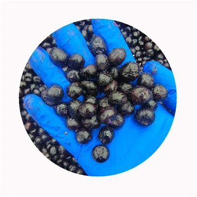 Gloved hand holding frozen blueberries above a larger batch